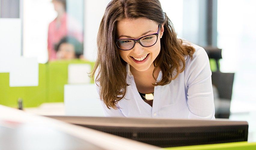 Veterinary practice manager standing at computer.
