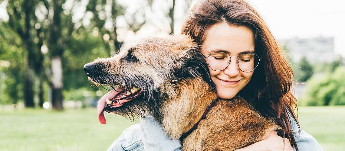 Woman hugging dog in a field.