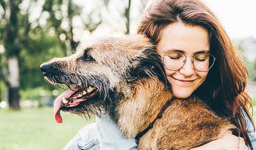 Woman hugging dog in a field.