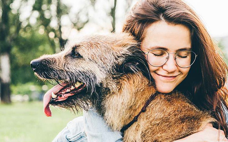 Woman hugging dog in a field.