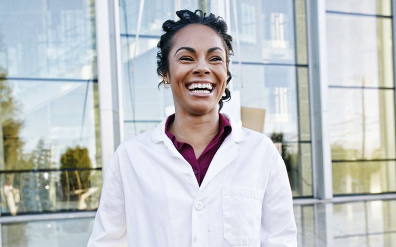 Happy, smiling veterinarian standing in front of the veterinary practice.