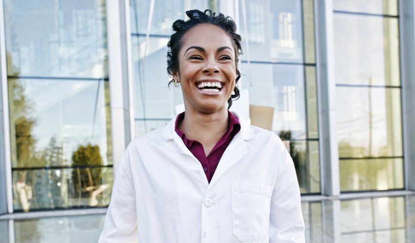 Happy, smiling veterinarian standing in front of the veterinary practice.