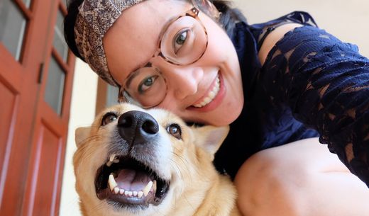 Asian woman taking a selfie with her dog while on the front step.