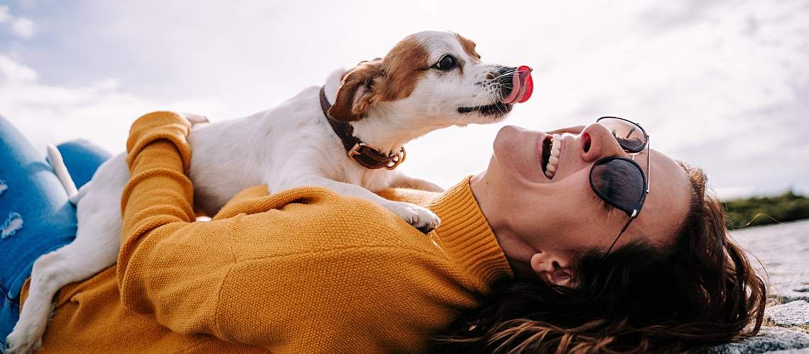 Woman laying down with dog on her.