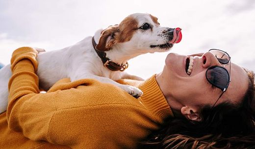 Woman laying down with dog on her.