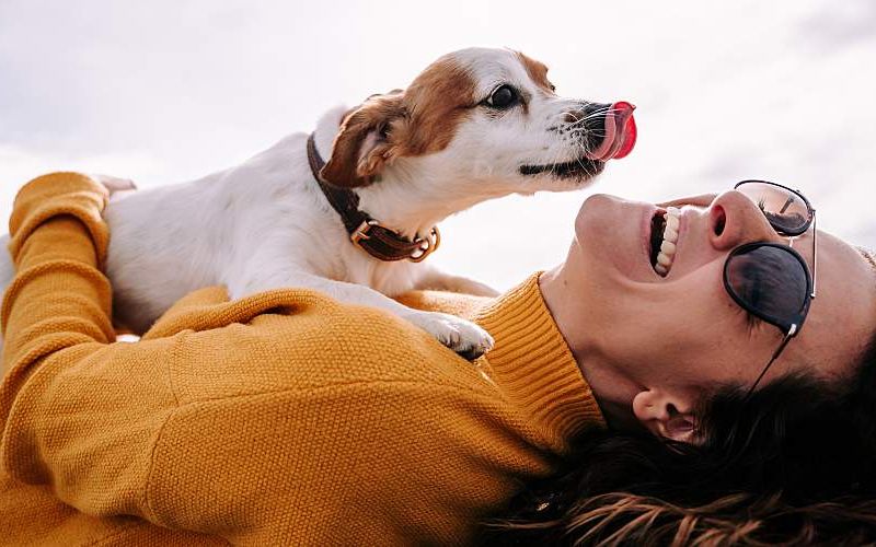 Woman laying down with dog on her.