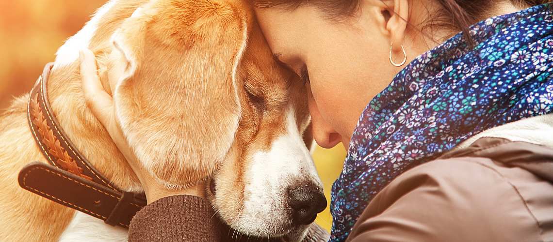 Stressed woman finds comfort hugging her dog.