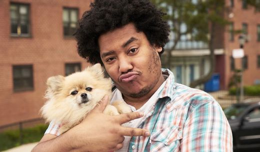 Millennial veterinary client holding dog and giving the peace sign.