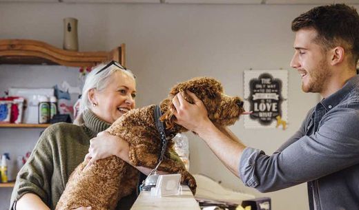 Veterinary receptionist greeting a female client and her dog.