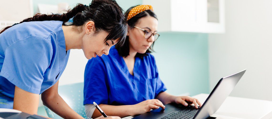 Veterinary professionals working at a laptop.