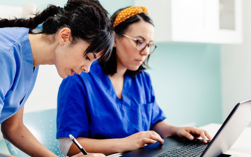 Veterinary professionals working at a laptop.