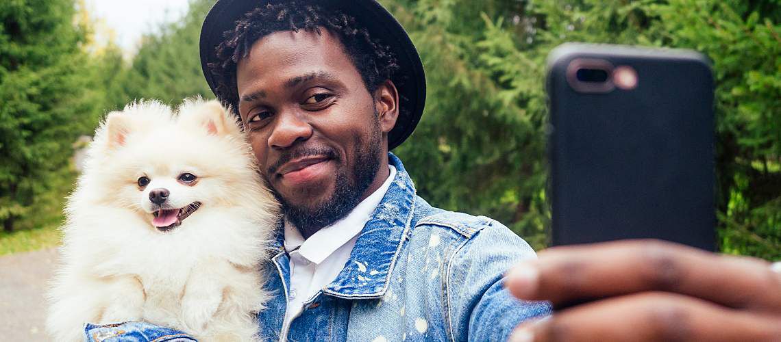 African American man taking a picture with his dog.