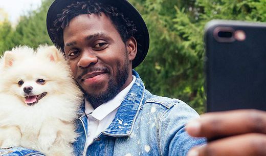 African American man taking a picture with his dog.