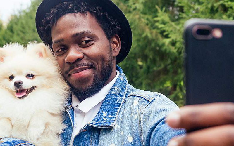 African American man taking a picture with his dog.