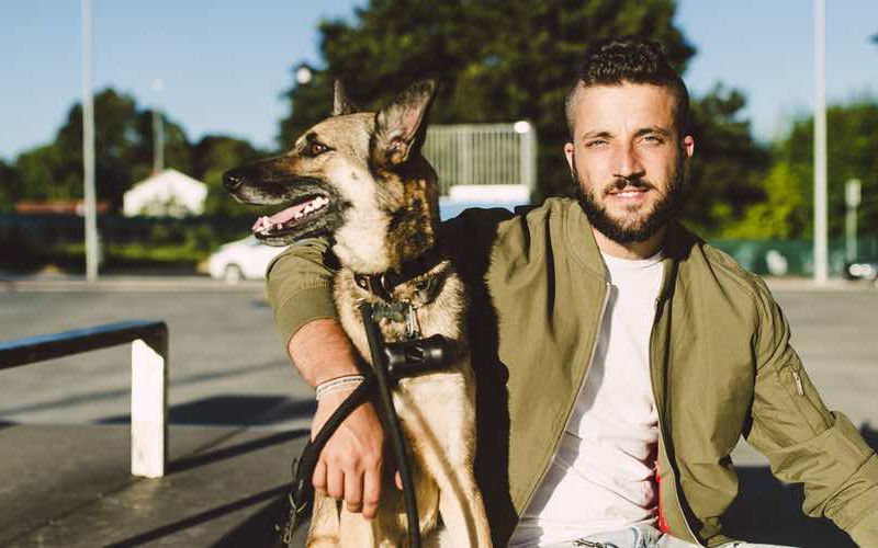 Millennial veterinary client sitting with dog on a bench.