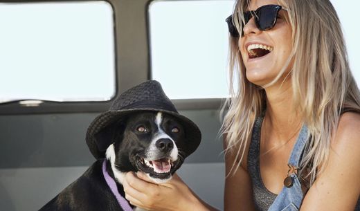 Woman sitting with dog wearing a hat.